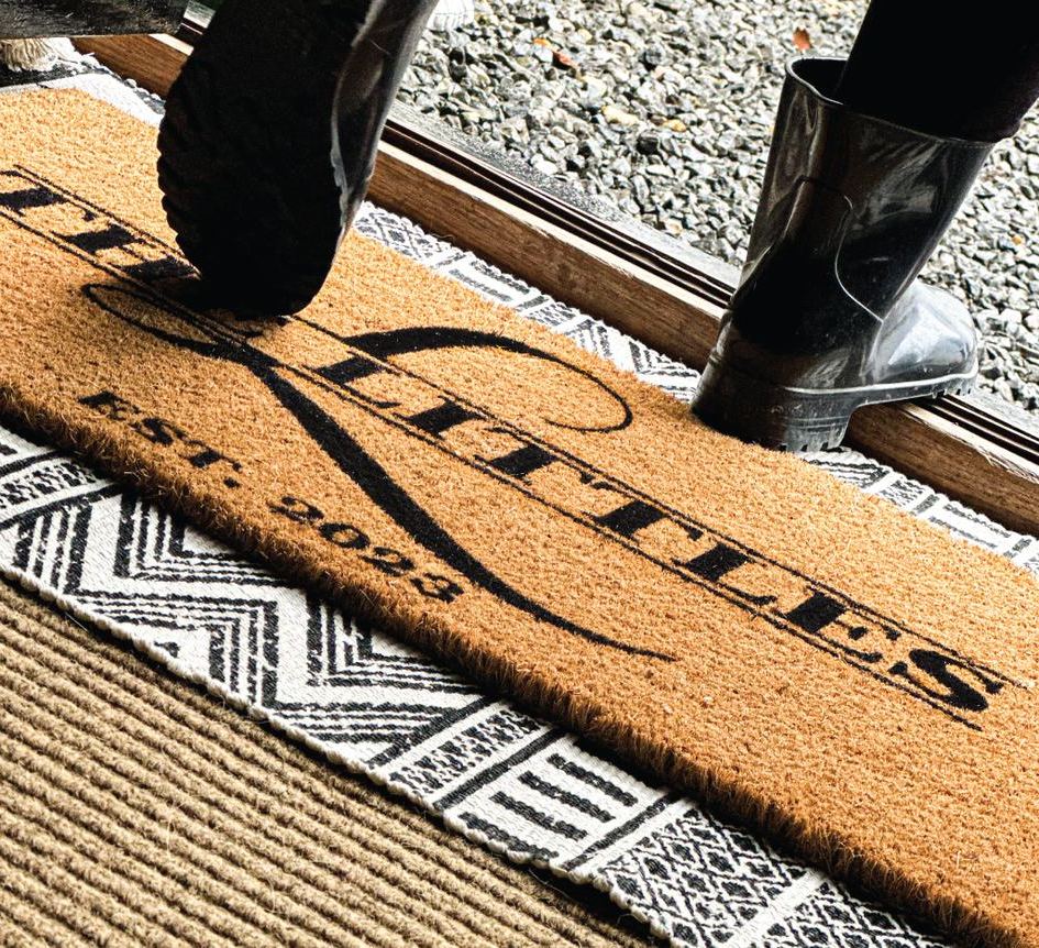 A personalised doormat reading The Littles, Est. 2023, with boots stepping across it
