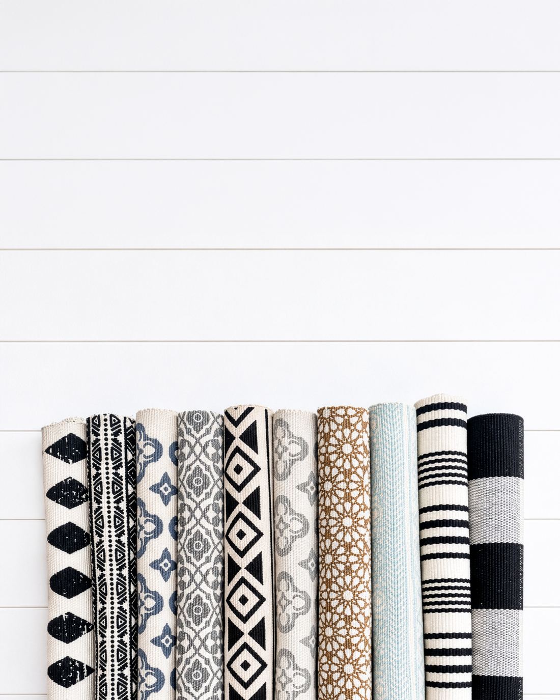 Rolled cotton layering rugs in black, grey, blue, caramel and aqua patterns